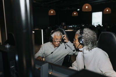 Senior couple talking while wearing headset sitting in gaming lounge