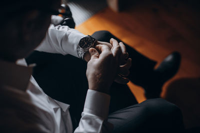 Midsection of man holding hands while sitting at home