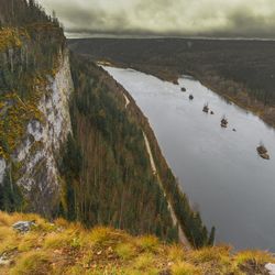 Scenic view of land by lake against sky