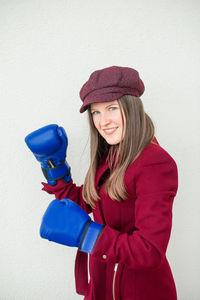 Portrait of smiling woman with boxing gloves against white background