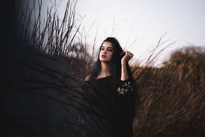 Portrait of young woman standing against sky