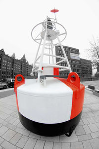 Red telephone booth on street in city against sky
