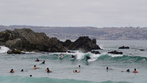 People on enjoying at sea against sky