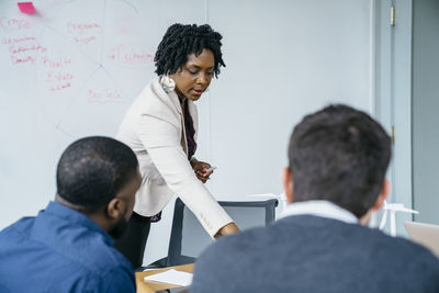 Businesswoman discussing with male colleagues while standing in office