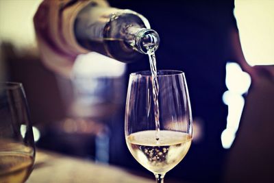 Midsection of waiter pouring wine in glass at restaurant