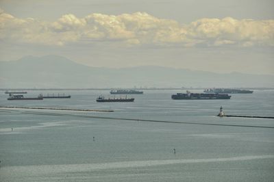 Boats in sea against cloudy sky