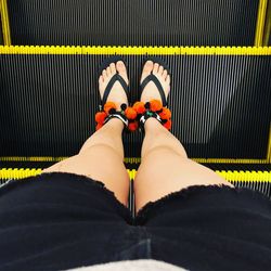 Low section of woman standing on escalator