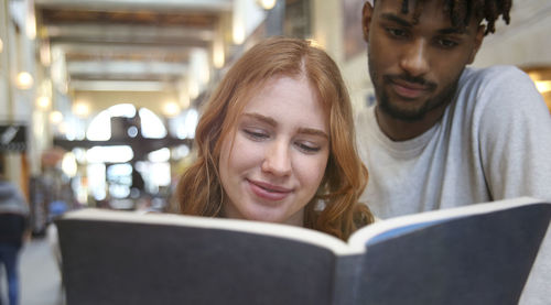 Close-up of boy and woman reading book