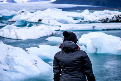 Rear view of man standing in frozen river