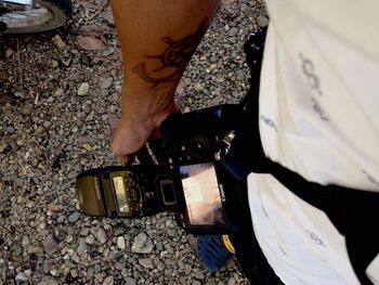 Low section of man holding camera while standing outdoors