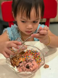 High angle view of cute girl eating desert while sitting at table