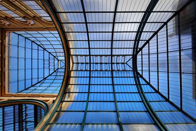 Low angle view of glass window against blue sky