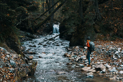 Man standing by waterfall in forest