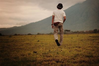 Rear view of man on field against sky