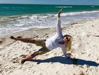 Full length of woman exercising at beach