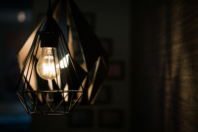 Close-up of illuminated light bulb hanging at home