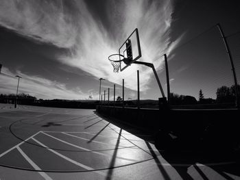 Low angle view of basketball hoop at court against cloudy sky