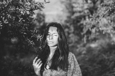 Young woman standing against plants