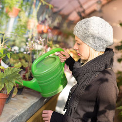 Side view of woman watering plants shop