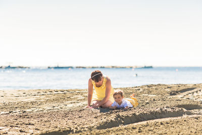 Siblings on beach against sky