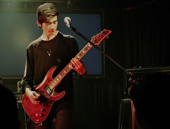 Teenage boy playing guitar during music concert 