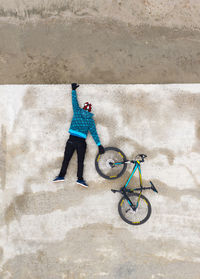Rear view of man hanging from a concrete wall and holding a wheel
