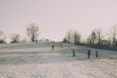 People on field against clear sky during winter