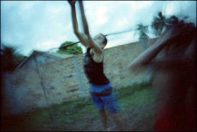 Midsection of woman with arms raised against sky