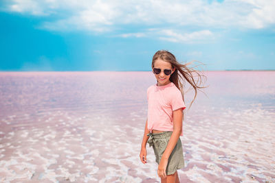 Woman wearing sunglasses on beach against sky