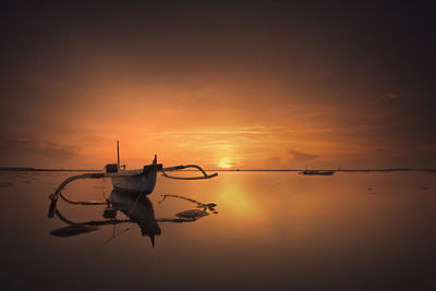 Silhouette birds flying over sea against sky during sunset