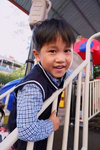Portrait of smiling cute boy by railing