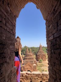 Rear view of woman standing by old historical building against sky