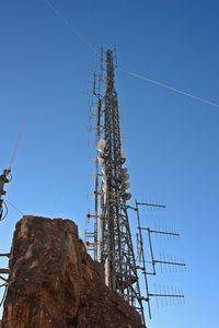 Low angle view of cranes against clear blue sky