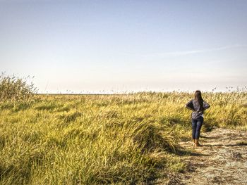 Rear view of woman standing on field against sky