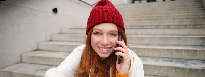 Portrait of young woman standing against wall