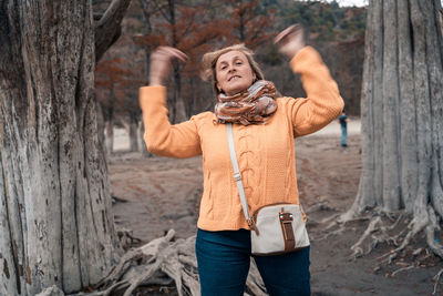 Portrait of woman standing on tree trunk