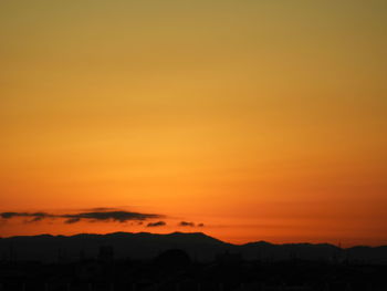 Scenic view of silhouette mountains against orange sky