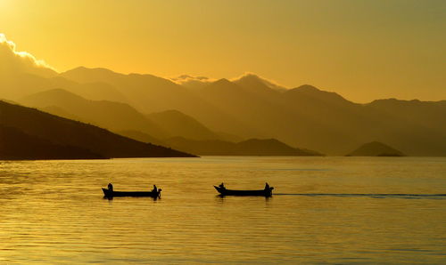 Silhouette boats in lake against sky during sunset