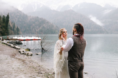 Happy newlyweds in love a man and a woman in wedding clothes embrace on the shore of the lake
