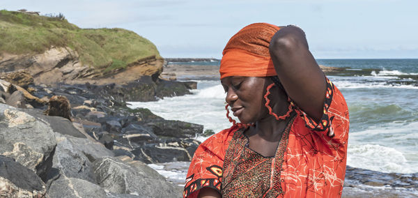 African woman with orange dress on the cliffs by the sea in sekondi-takoradi ghana west africa