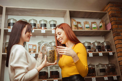 Woman chooses tea in store, natural chinese herbs in glass jars on wind. private 