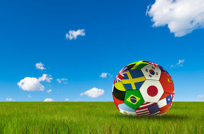 Colorful ball on field against blue sky