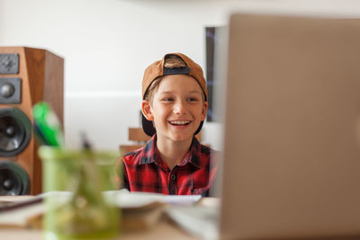 Happy boy talking to someone during a video call over a computer in the living room.