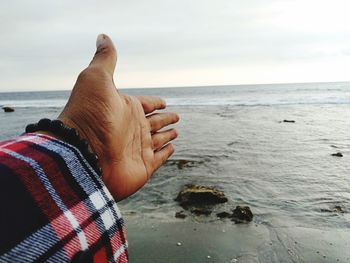 Midsection of person on beach against sky