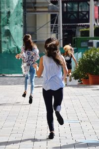 Full length of girls walking on sidewalk in city