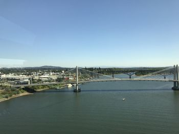 Bridge over river in city against clear sky