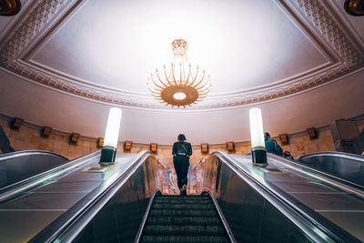 Rear view of woman standing on escalator