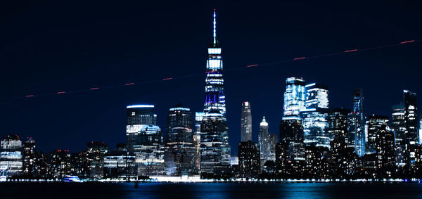 Illuminated modern buildings in city against sky at night