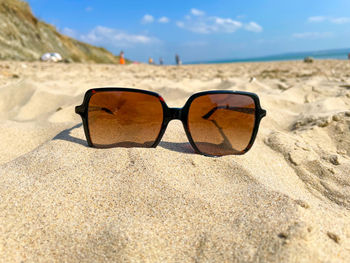 Close-up of sunglasses on beach during sunny day