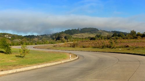 Road amidst green landscape against sky